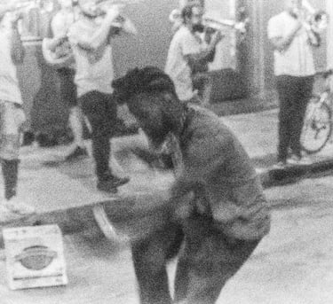 a man dancing on the street with brass band in the background
