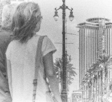 a man and woman walking down a street and watching a high bulding