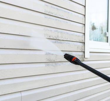 House with dirt and grime being cleaned with a pressure washer