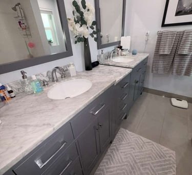 Modern bathroom with double vanity, grey cabinets, white marble countertops, and large mirrors.