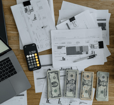 computer on table with financials and money