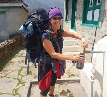 Karen Felton, filling a water bottle while trekking in the Nepal Himalaya