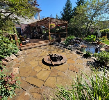 A fire pit in a backyard with a custom paver patio and pergola