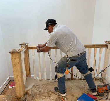a man in a white shirt and jeans standing on a stair rail