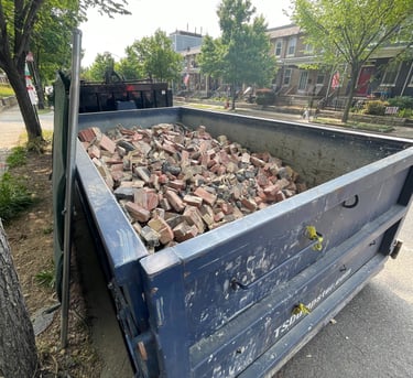 a blue dumpster truck with bricks in the back