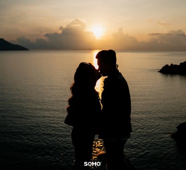 a couple kissing in front of a sunset