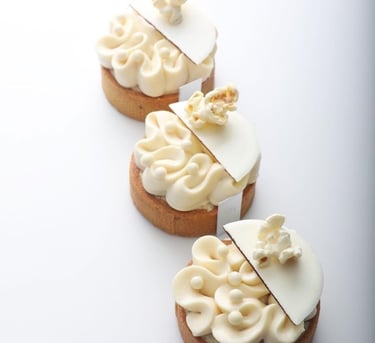 a row of three cakes with white frosting