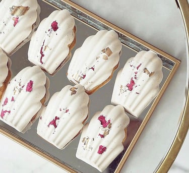a tray of cookies with white frosting and pink flowers
