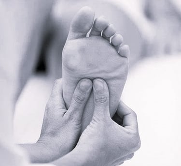 Une personne masse un pied et une jambe  / réflexologie