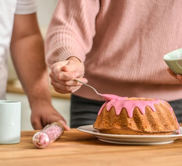 mulher colocando cobertura de morango em um bolo