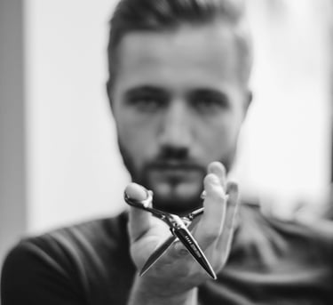 Barbero profesional sosteniendo tijeras de corte de cabello afiladas en un retrato en blanco y negro