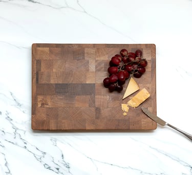 Overhead view of a wooden chopping board styled with grapes, cheese and a knife