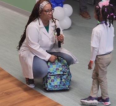 Shenell giving away a STEM themed book bag filled with her books to a child