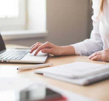 a woman sitting at a desk with a laptop and a notebook