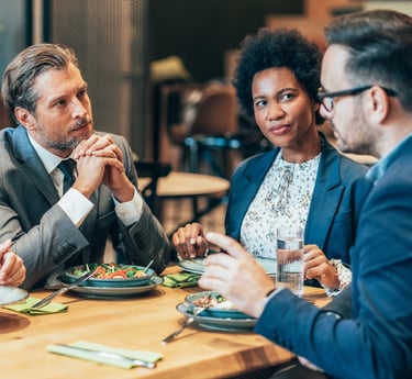 a group of people sitting at a table with food