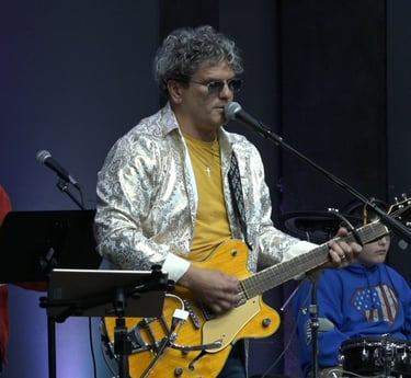 a man playing guitar and singing into a microphone