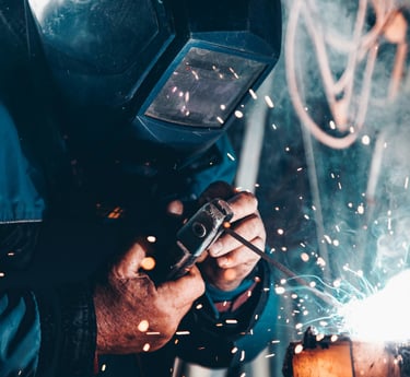 Soudeur en plein travail, portant un masque de protection, avec des étincelles de soudure