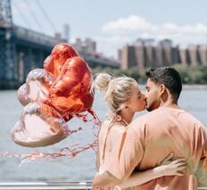 a man and woman kissing on a bridge over a river