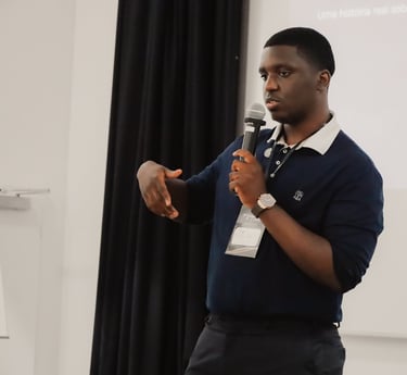 A young Black man giving a presentation with a microphone at a professional seminar.