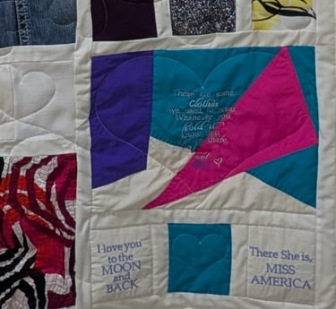 Memory quilt pieced from fabric cut from clothing with an embroidered message on the bottom right