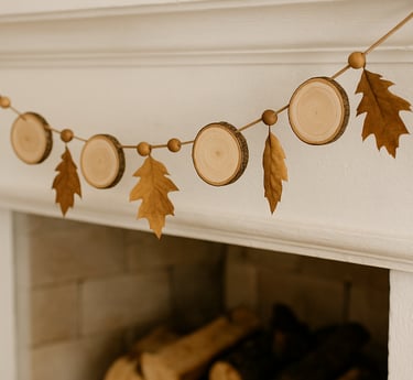 Rustic garland of wood slices, beads, and dried leaves strung across a white fireplace mantel