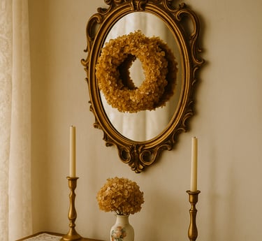 Entryway table with lace runner, brass candlesticks, dried hydrangeas, and a gold-framed mirror.
