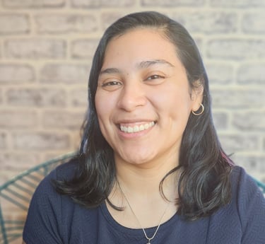 Headshot image of Karen wearing a blue blouse against a brick backdrop.