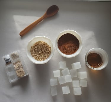Clear melt-and-pour soap base cubes, small bowls of ground coffee and rolled oats