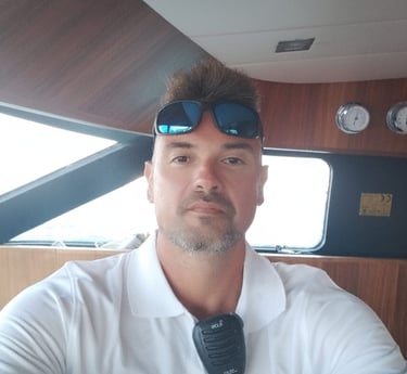 a man in a white shirt and sunglasses, yacht skipper