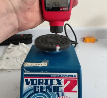 agitador vortex en calibración con tacómetro sobre mesa de laboratorio
