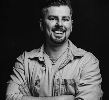 Albert Heit, lächelnd mit verschränkten Armen vor dunklem Hintergrund