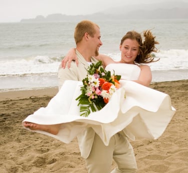 Groom spinning bride on Baker Beach in San Francisco