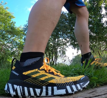 a person standing on a log in the woods weating adidas trainers