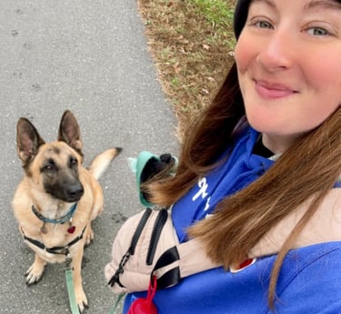 a woman in a blue jacket and hat with a dog on a leash