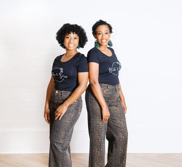two women standing next to each other in front of a white wall
