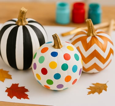 hree painted pumpkins on a craft table: one with bold black-and-white vertical stripes