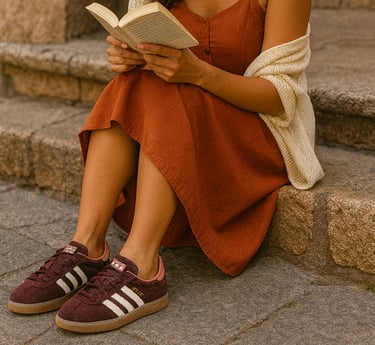 Woman sitting on stone steps reading a book in a burnt orange dress and cream cardigan, styled with 