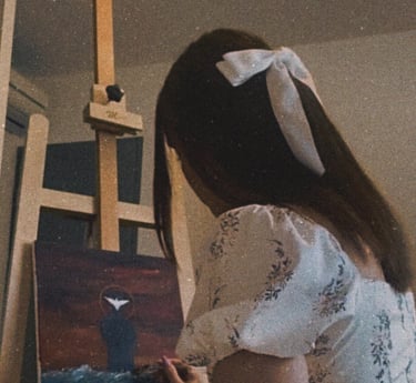 Une jeune femme dans une robe blanche avec un noeud blanc dans les cheveux en train de peindre