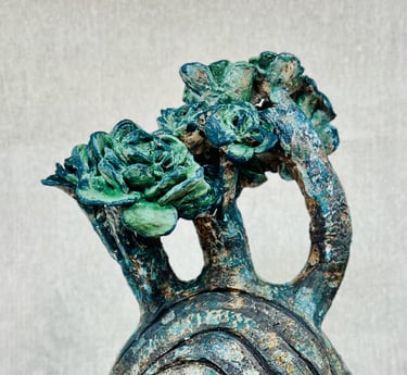 A ceramic plant-like sculpture glazed in green, blue and brown tones