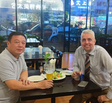 Two business colleagues enjoying dinner and beer at a city restaurant table with window views.