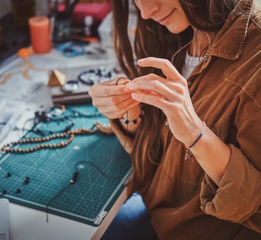 Un joyero elaborando un collar de cuentas hecho a mano materiales de artesanía.