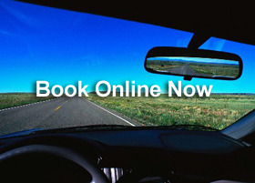 View from a car driving on an open highway with Book Online Now text for travel reservations.