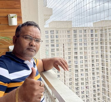 A happy customer standing beside their balcony secured with a neatly installed pigeon net by Arjilli