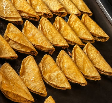 Tacos dorados de Barbacoa recién preparados en plancha caliente, con tortilla de maíz crujiente.