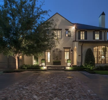 a large house with brickwork and a brick wall and lighting planters at front steps