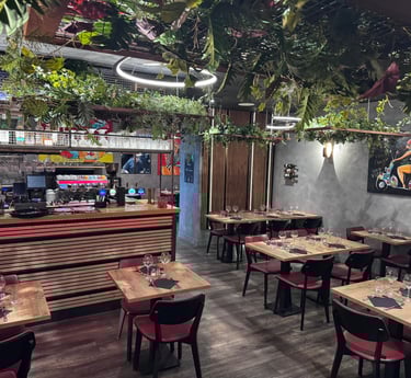 Modern restaurant interior featuring a stylish bar, wooden tables, and lush hanging plants.