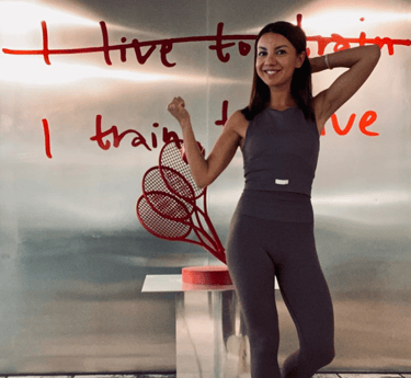 a woman in a gray top and leggings and a tennis racket