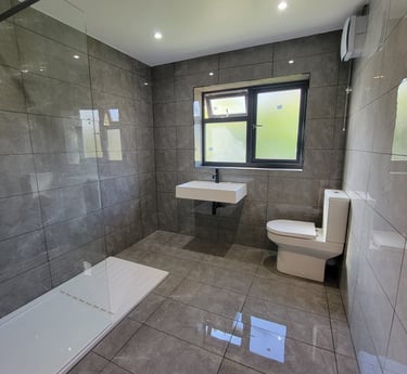 Completed family bathroom in Birmingham with modern tiles and wall mounted sink 