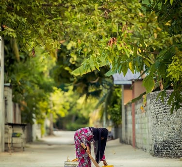 a woman in a pink dress is cleaning a sidewalk