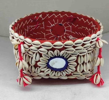 "Decorative bamboo basket wrapped in red fabric with shell embellishments and floral garland–Meant for export"